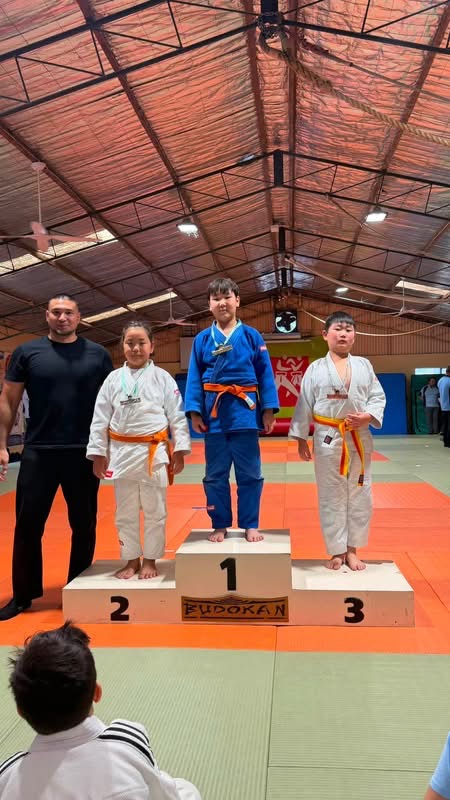 Judo athletes and coach at a medal presentation