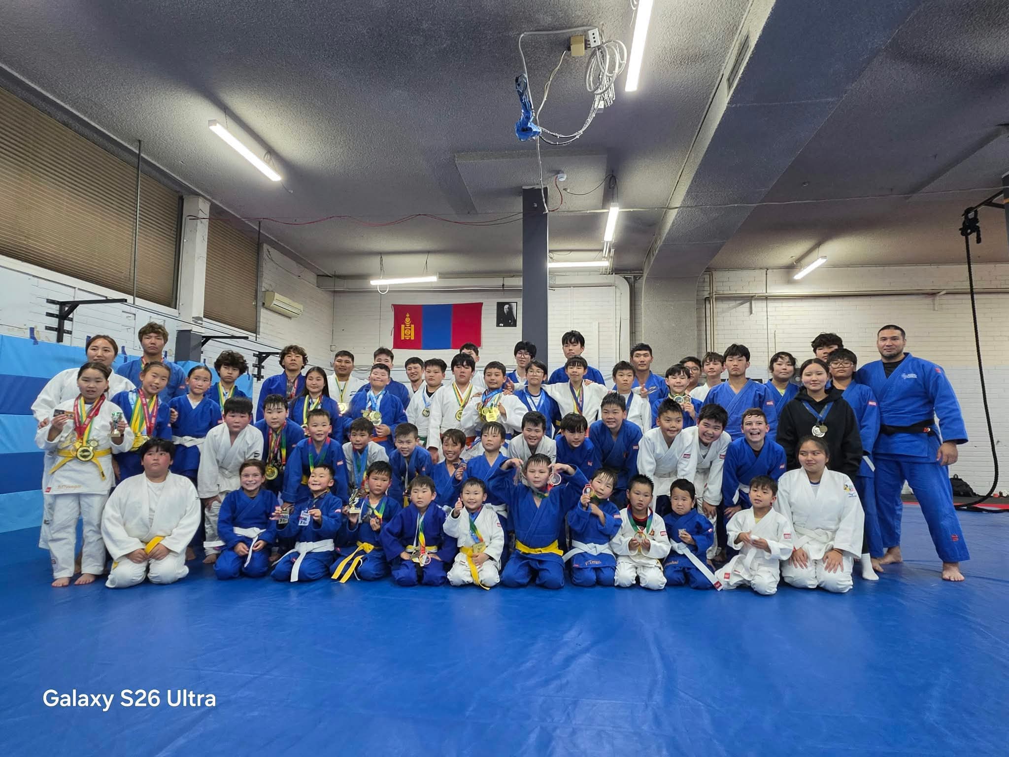 Judo students and coaches posing with their medals
